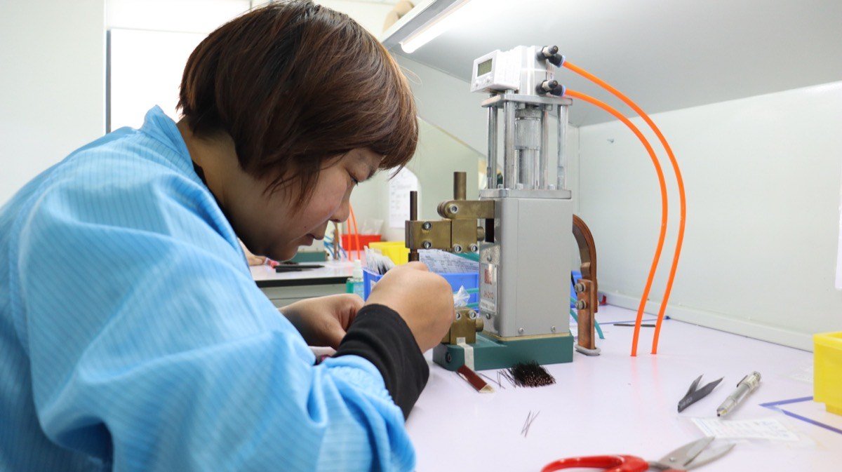 Endotec technician hand-assembling fiber optic light guide bundle